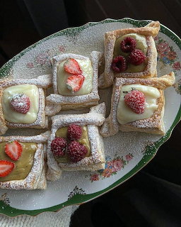 Square puff pastry tarts with custard filling, topped with fresh strawberries and raspberries, dusted with powdered sugar