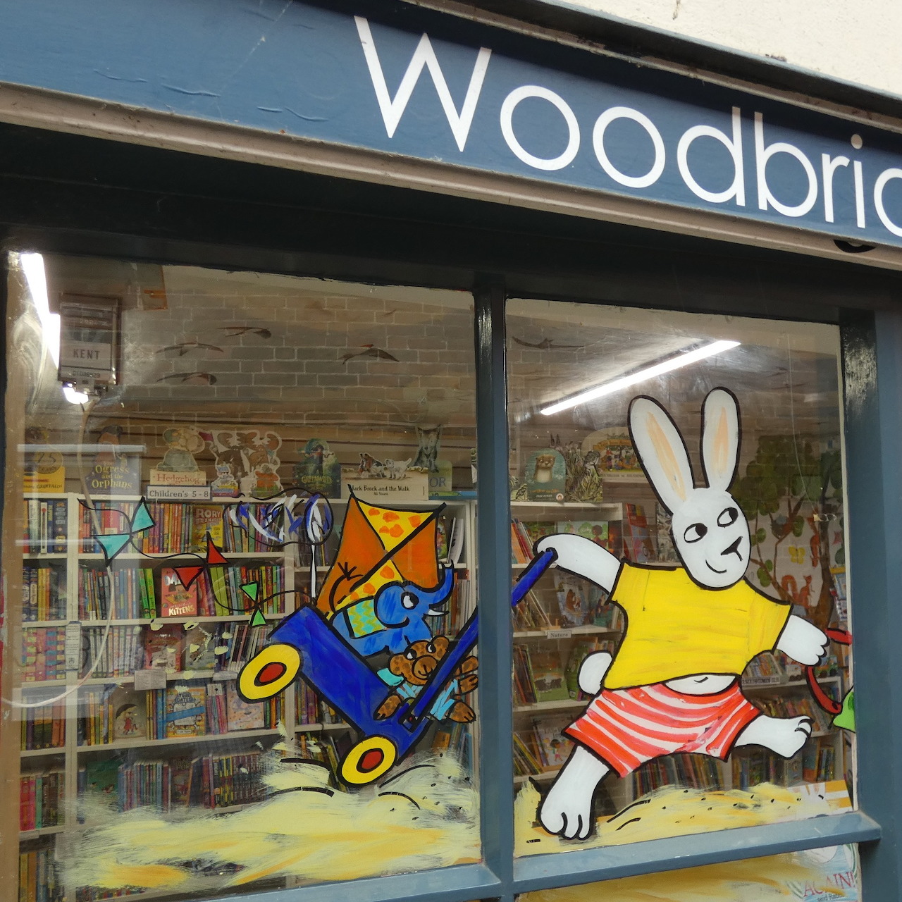 Shop window with a painted cartoon rabbit and blue airplane, with books visible inside
