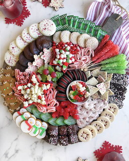 Round Christmas charcuterie board with candy canes, cookies, chocolates, marshmallows, and festive holiday treats
