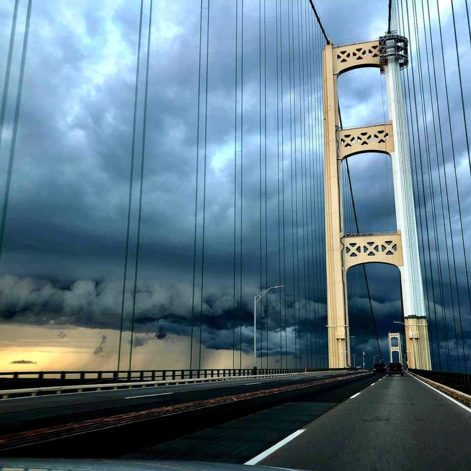 Mackinac Bridge tower under dark storm clouds with dramatic sky
