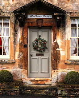 Grey front door with Christmas wreath on a honey-stone Cotswolds cottage, Glenthorne House sign above