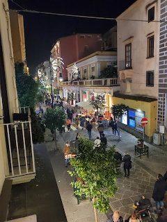 Nighttime street in Sorrento with people walking between old buildings and decorative lights