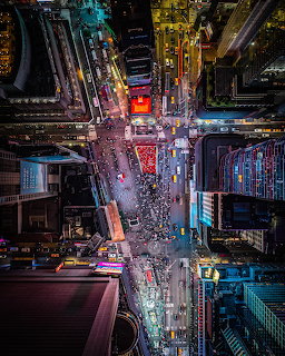 Aerial night view of Times Square in New York City with bright lights, crowds, and traffic