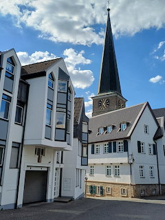 Historic white buildings and a tall church spire under a blue sky in an old town setting