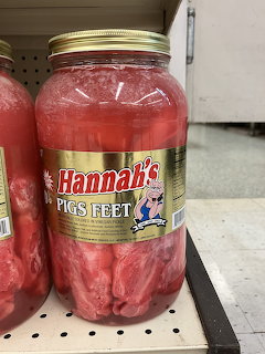 Glass jars of pickled pigs feet in pink brine on a retail shelf