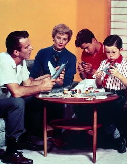 Leave It to Beaver cast building model airplanes around a table in1950s color promotional photo