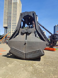 Large metal sculpture of a friendly excavator digger with a smiling face in an urban plaza