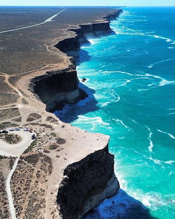 Aerial view of dark sea cliffs and turquoise ocean along a rugged Australian coastline