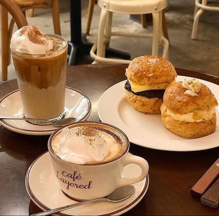 Two coffee drinks and scones on plates at a café table