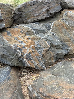 Gray weathered rocks with orange lichen and natural fracture lines