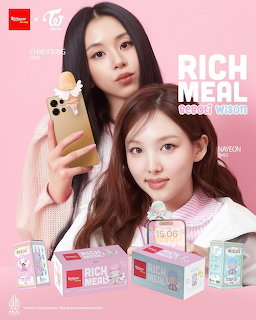 Nayeon and Chaeyoung from TWICE posing with Richeese Factory Rich Meal product boxes on a pink background