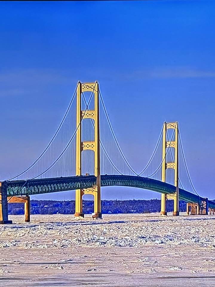 Yellow suspension bridge over frozen water under blue sky in winter