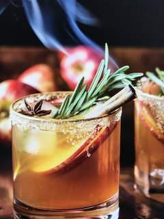 Apple cider cocktail with rosemary, apple slice garnish, and sugared rim in a rocks glass