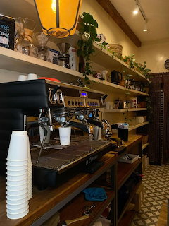 Cozy coffee shop interior with espresso machine, wooden shelves, and warm lighting