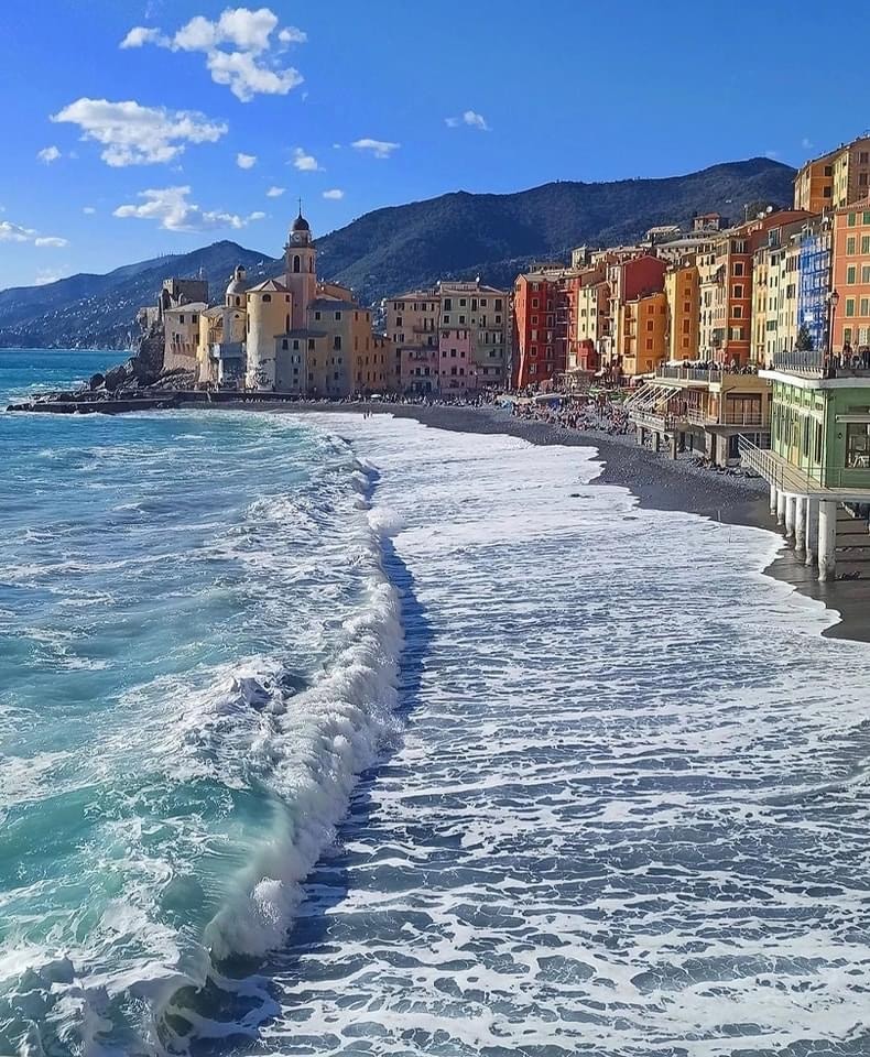 Aerial view of colorful Italian coastal town with beach, turquoise sea, and mountains