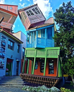 Colorful leaning traditional houses with wooden balconies in Tbilisi old town against blue sky