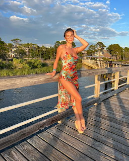 Woman in floral dress posing on a wooden dock over water at golden hour