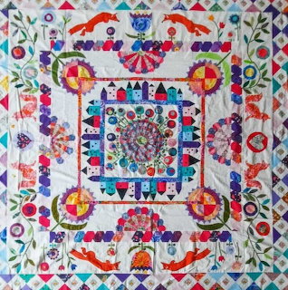 Colorful symmetrical folk art quilt with foxes, flowers, and geometric patterns