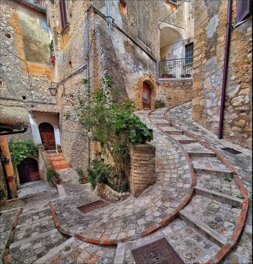 Curved stone staircase in rustic courtyard with brick walls and green plants