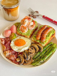 Breakfast plate with avocado toast, fried egg, bacon, mushrooms, asparagus, sausages, and coffee on wooden table