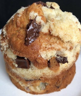 Close-up of a chocolate chunk muffin with crumb topping on a white plate