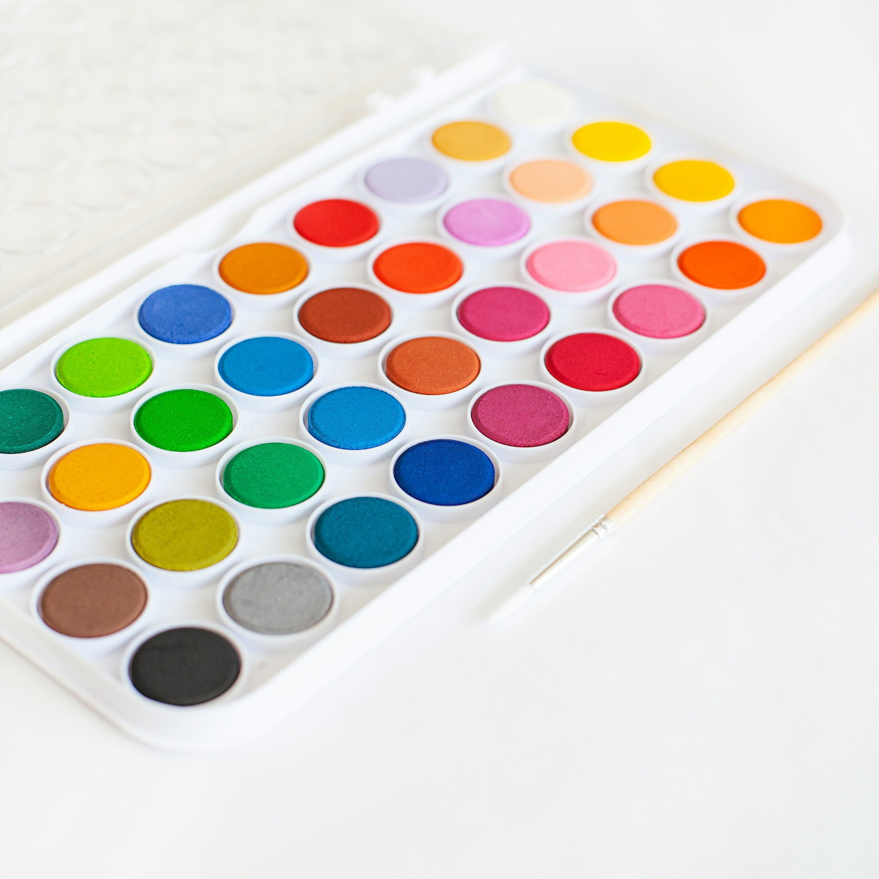 Watercolor paint palette with colorful paint pans on a white tray