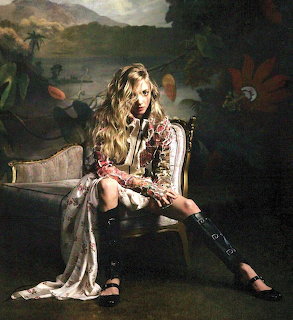 Woman in floral dress sitting on antique chair with painted tropical landscape background
