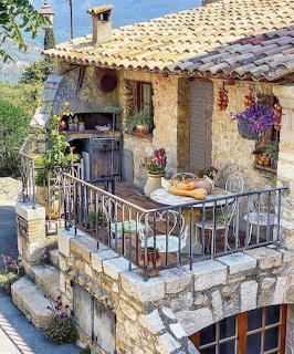 Stone house terrace with table, chairs, flowers, and coastal view in Capri