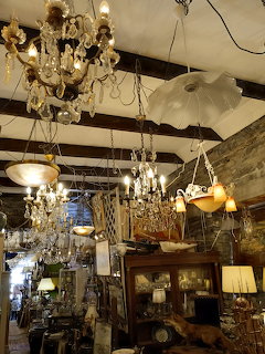 Interior of an antique shop with chandeliers, lamps, and vintage wooden furniture