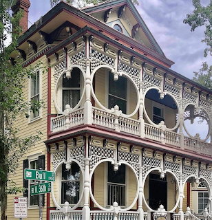 Ornate Victorian house with lace trim and wraparound porch on a street corner