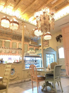 Luxurious cafe interior with ornate chandeliers, wood ceiling, white cabinets and elegant seating