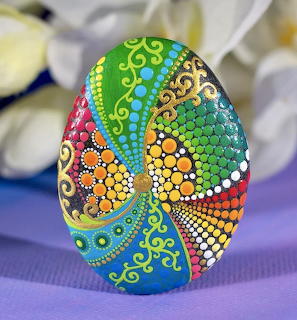 Hand-painted egg with colorful mandala dot art patterns in rainbow sections on purple cloth