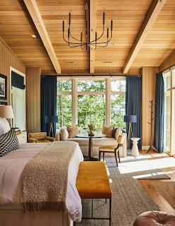 Cozy bedroom with natural wood beam ceiling, chandelier, large windows, and neutral decor