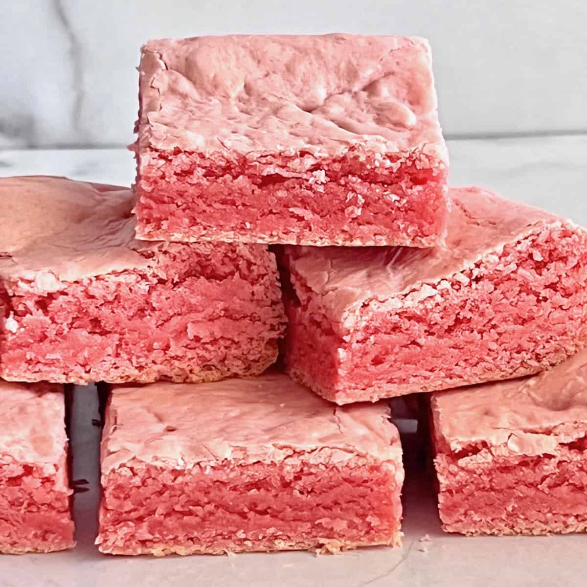 Stack of pink strawberry brownies on a light marble surface