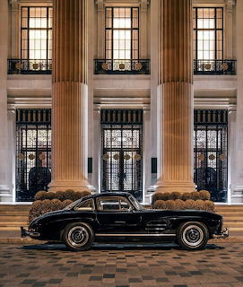 Vintage black car parked before a grand columned building at night