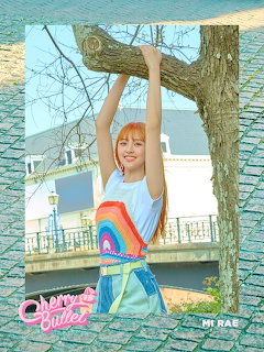 Young woman in a rainbow top and denim shorts posing under a tree outdoors