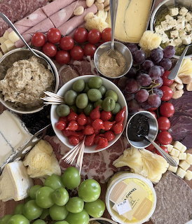 Overhead charcuterie board with cheese, meats, grapes, olives, strawberries, crackers, and dips