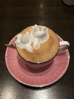 White cat-shaped 3D latte art on cappuccino in pink cup and saucer