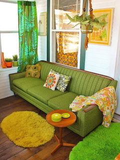 Retro living room with green mid-century sofa, yellow shag rug, colorful pillows, and hanging plants