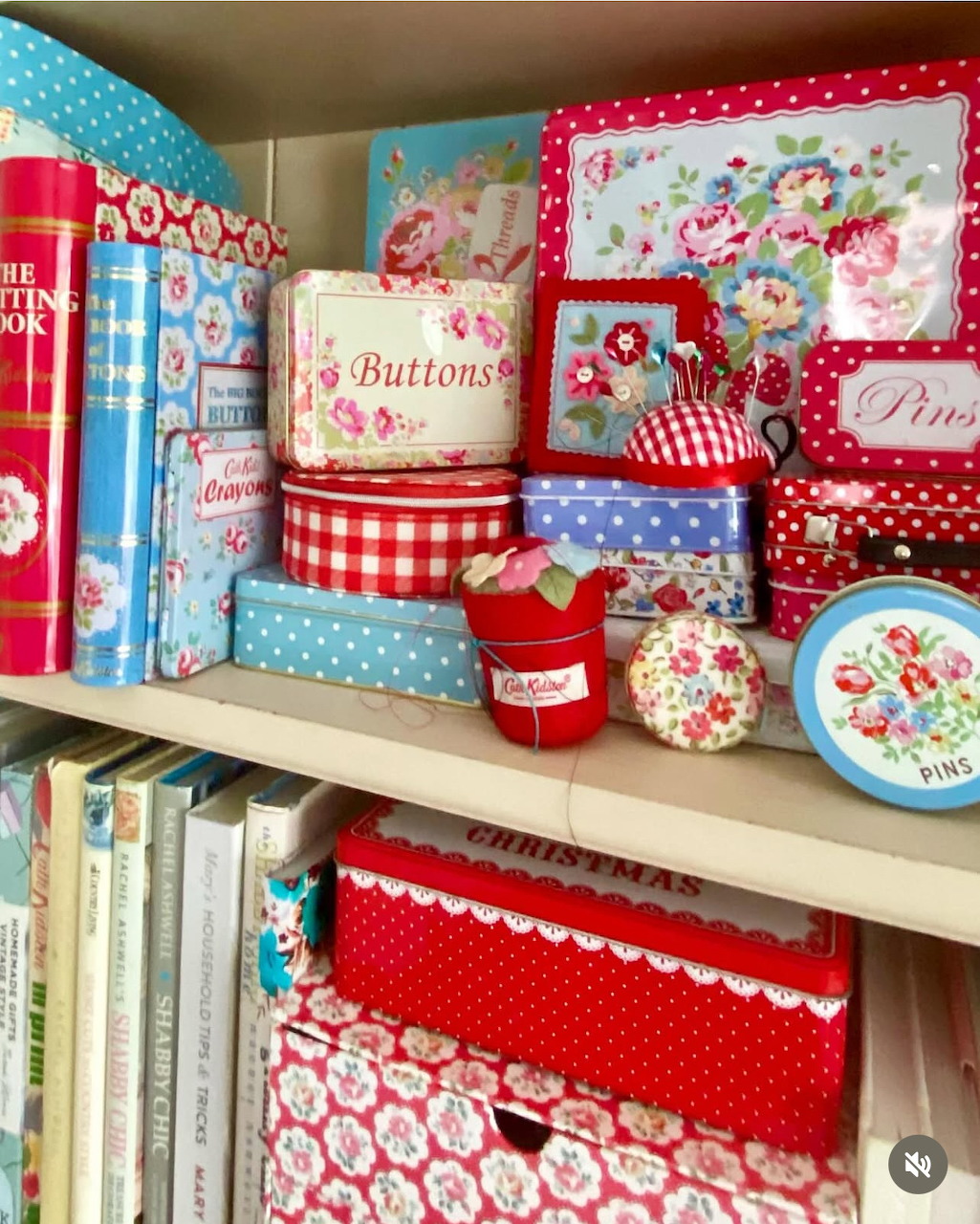 Colorful shelf with vintage floral tins, polka dot boxes, buttons jar, and craft books in red and blue