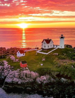 Nubble Lighthouse on a rocky island at sunset with orange sky and ocean