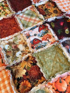 Patchwork rag quilt with fall themed fabric squares including pumpkins, sunflowers, and autumn patterns