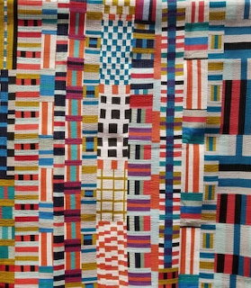 Colorful patchwork quilt with geometric striped pattern in multiple bright colors