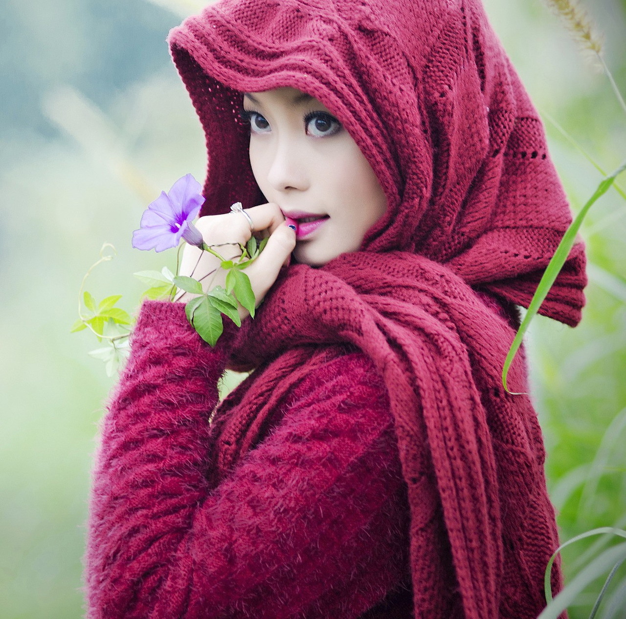 Woman in burgundy headscarf holding purple flowers in outdoor portrait