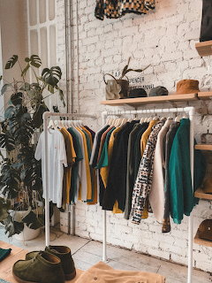 Clothing rack with shirts and jackets in a boutique interior by a white brick wall