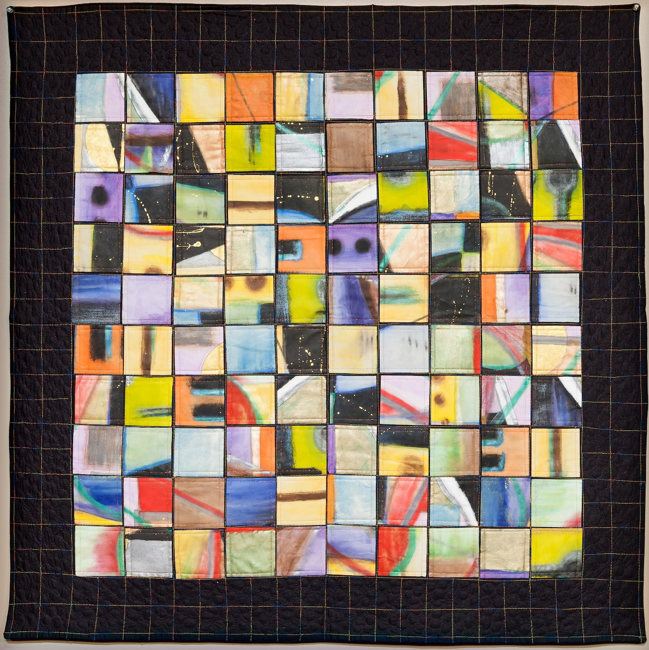 Colorful patchwork quilt with abstract geometric squares arranged in a grid pattern on black fabric