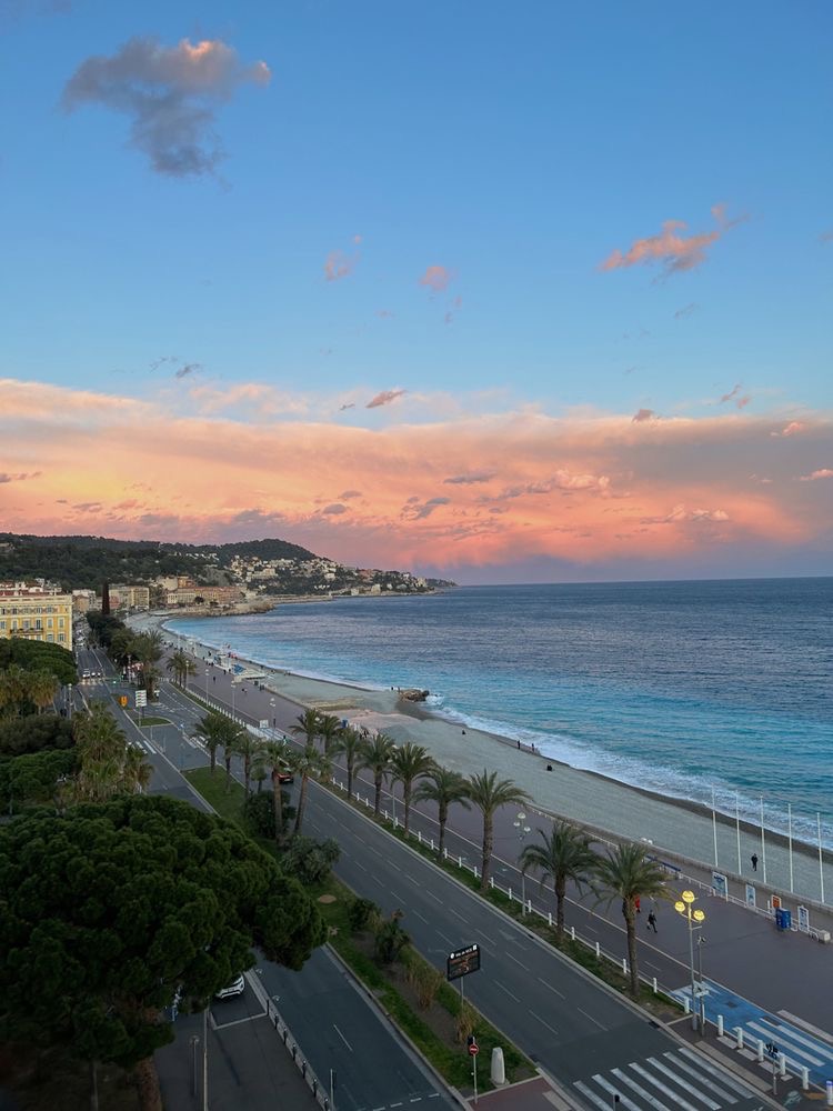 Monaco coastline at sunset with promenade, beach, and colorful sky over Mediterranean Sea