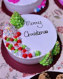 Round white Christmas cake with piped Santa Claus, Christmas tree decorations, and Merry Christmas text