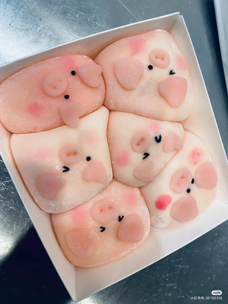 Five pink pig-shaped mochi pastries in a white box