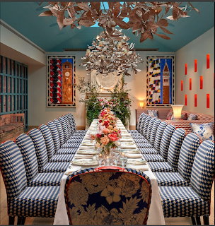 Elegant dining room with striped chairs, long table setting, flowers, and warm lighting